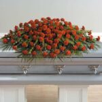 Casket adorned with a large, elegant arrangement of red roses.