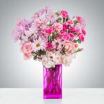 Vibrant pink and white floral arrangement in a tall purple vase.