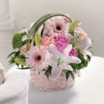 Elegant basket of pink and white flowers with greenery.