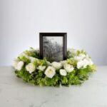 A framed black and white photo surrounded by a white and green floral wreath.