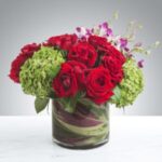 Elegant bouquet of red roses and green hydrangeas in a glass vase.