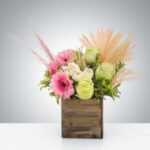 Elegant floral arrangement in a wooden box with pink and white flowers.