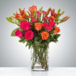 Bright pink and orange flowers in a clear glass vase.