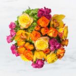 Vibrant bouquet of multicolored roses on a white marble background.