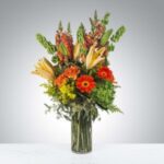 Elegant bouquet with vibrant orange and red flowers in a clear glass vase.