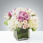 Elegant bouquet of pink and white flowers in a square glass vase.