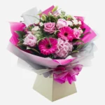 A vibrant bouquet of pink flowers wrapped in white and pink paper.