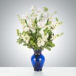 Elegant white flowers arranged in a deep blue vase.
