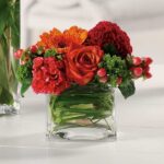 Vibrant mixed flower arrangement in a clear square vase.