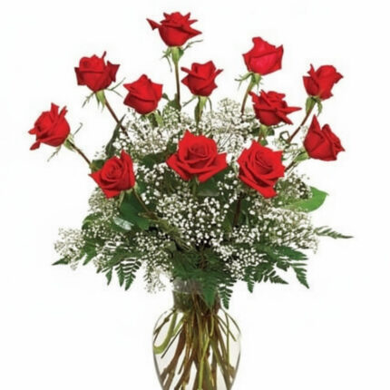 A bouquet of red roses with greenery in a clear vase.