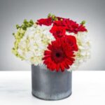 A bouquet of red and white flowers in a striped vase.