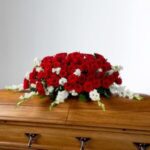 Red and white flower arrangement on a wooden coffin.