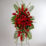 Elegant standing spray of red roses with lush greenery.