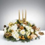 Elegant floral centerpiece with white roses and gold candles.