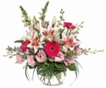 A vibrant bouquet with pink lilies and gerbera daisies in a clear glass vase.