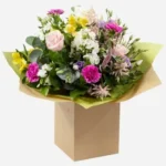 A colorful mixed flower bouquet arranged in a brown box.