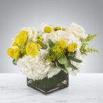 Elegant bouquet of white and yellow flowers in a clear glass vase.