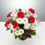 Elegant bouquet with red and white flowers in a dark vase.