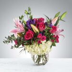 A vibrant bouquet of mixed flowers in a clear glass vase.