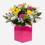 Colorful flower arrangement in a bright pink box.