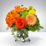 A vibrant bouquet of orange and yellow flowers in a clear glass vase.