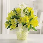 Bright yellow and white flowers arranged in a decorative vase.