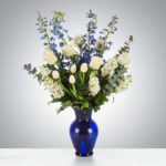 Elegant bouquet of white and blue flowers in a blue vase.
