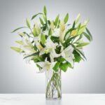 Elegant bouquet of white lilies in a clear glass vase.