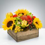 Bright sunflowers and colorful blooms in a rustic wooden box.