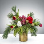 Elegant Christmas floral arrangement with red, white, and purple flowers in a gold vase.