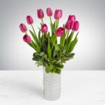 A bouquet of vibrant pink tulips in a white vase.