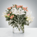 Elegant flower arrangement with white lilies and pink accents in a clear vase.