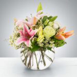 A vibrant flower arrangement in a round glass vase.