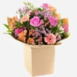 Vibrant mixed flower bouquet in a beige box.