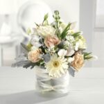 Elegant bouquet of white and pale peach flowers in a glass vase.