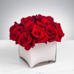 Elegant bouquet of red roses in a white square vase.