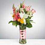 Elegant bouquet with pink roses, white lilies, and vibrant yellow flowers in a clear vase.