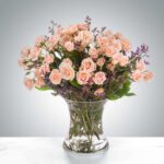 A bouquet of peach roses in a clear glass vase.