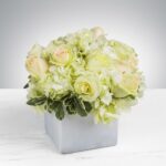 Elegant white and cream flower arrangement in a square vase.