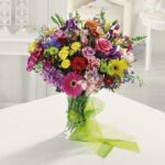 A vibrant mixed bouquet of various flowers in a clear glass vase.