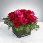 Elegant bouquet of red and pink roses in a modern glass vase.
