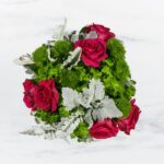 A bouquet with vibrant red roses and green foliage on a white background.