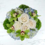 Elegant bouquet with white roses, green orchids, and hydrangeas.