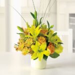 Bright yellow and orange flower arrangement in a white vase.