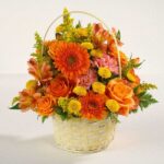 Vibrant orange and yellow flower arrangement in a white woven basket.