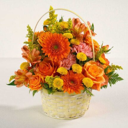 Vibrant orange and yellow flower arrangement in a white woven basket.