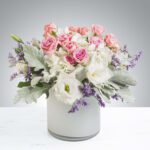 Elegant bouquet of pink roses and white flowers in a white vase.