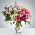 Elegant bouquet of pink lilies and roses in a clear vase.