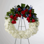 A floral wreath with red, white, and blue flowers on a stand.