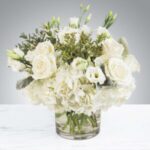 Elegant white floral arrangement in clear glass vase.